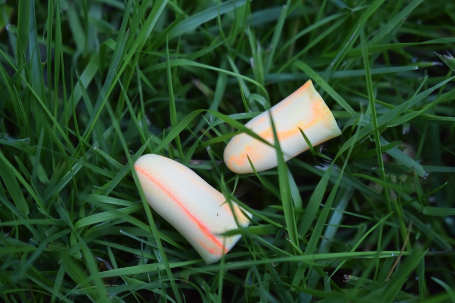 Yellow foam earplugs discarded in grass